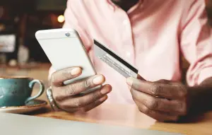 Man using his phone to make a purchase while holding his credit card