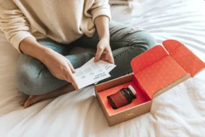 Person sitting in their bed with an opened box containing a bottle of pills