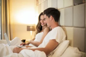 a man and lady lying in bed smiling at each other