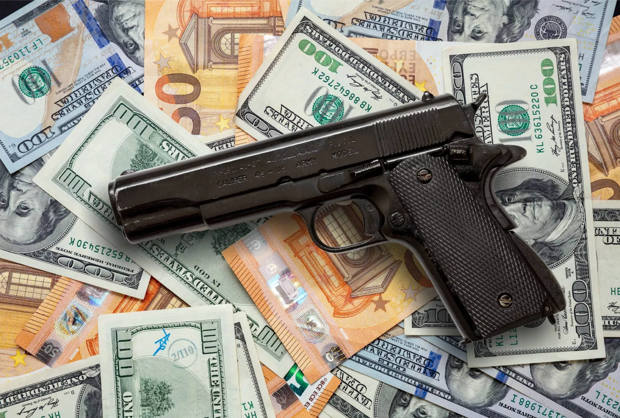 a hand gun resting on a pile of money that you could make if you sell guns