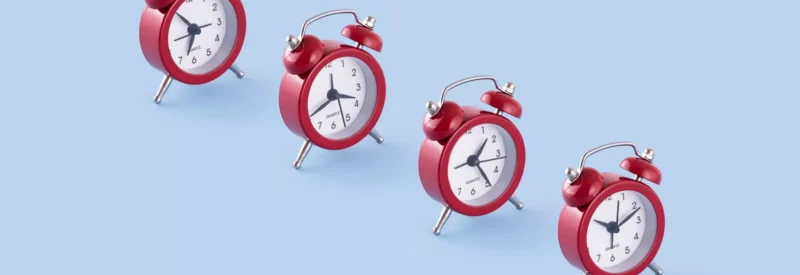 red ticking clocks against blue background symbolizing the question of how long does it take to buy a gun