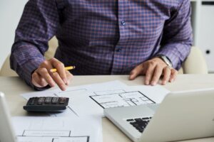 person going over paperwork with calculator overhead costs for small business