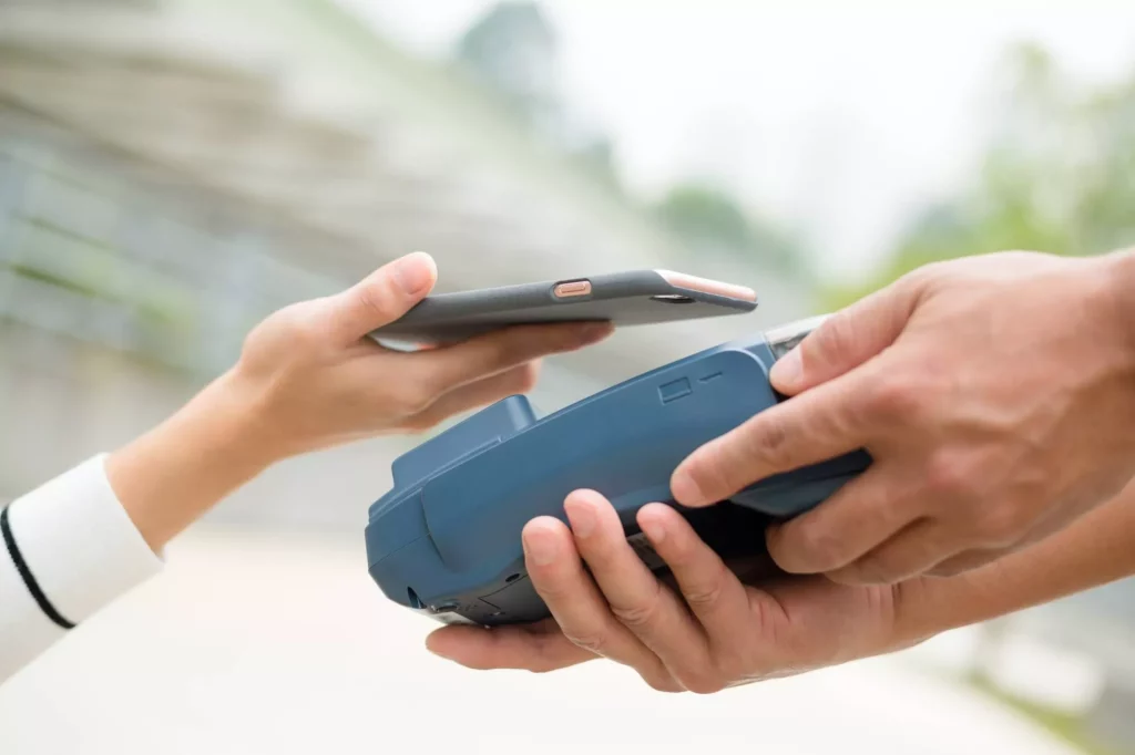 woman using phone to process payment to a terminal