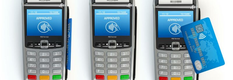 3 emv terminals that has a emv credit card in the middle terminal and another credit laying on top of the third terminal
