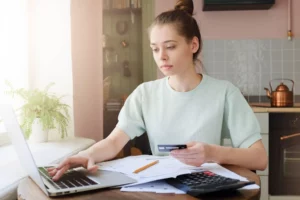 woman holding credit card and typing into laptop to deduct business card fees from taxes