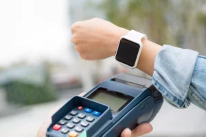 hand holding a reader with NFC technology taking a contactless payment from a smart watch