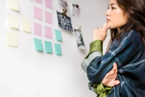 woman looking at notepads on white wall as she contemplates how to start your own business