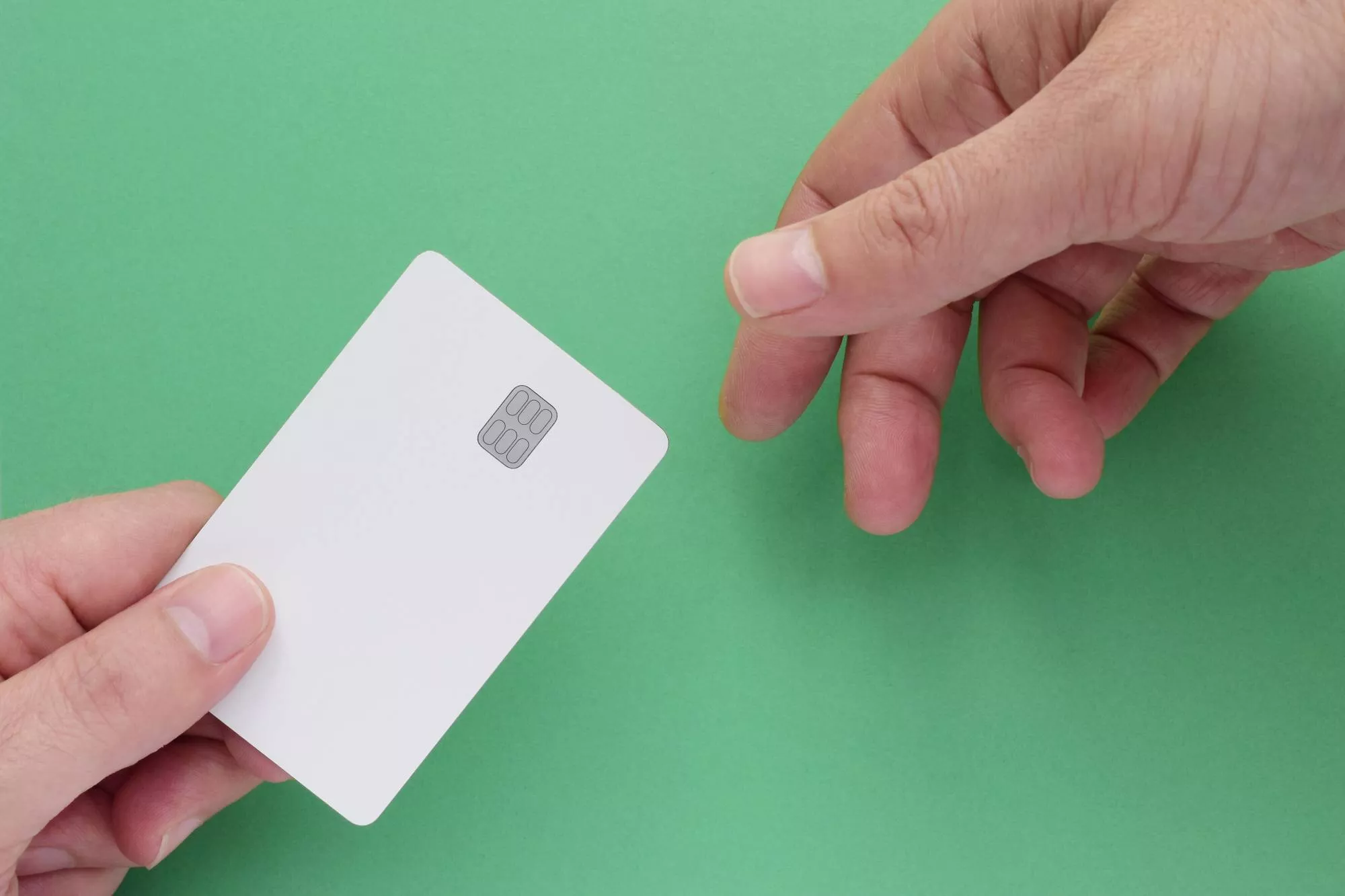 credit card that will be processed with a payment service provider being handed from one hand to another hand against a green background