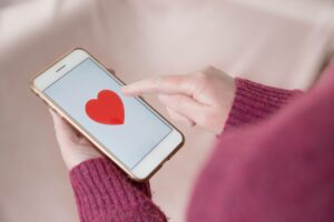 woman holding iphone with heart on screen after learning how to create a dating website