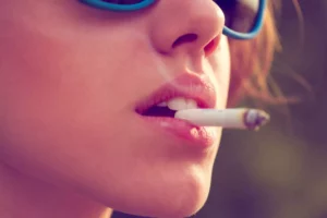 woman wearing sunglasses and smoking a cigarette and thinking about how to get a tobacco license