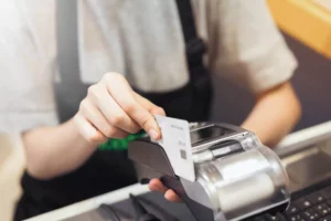 cashier swiping a credit card on a terminal where it will process with the merchant ID