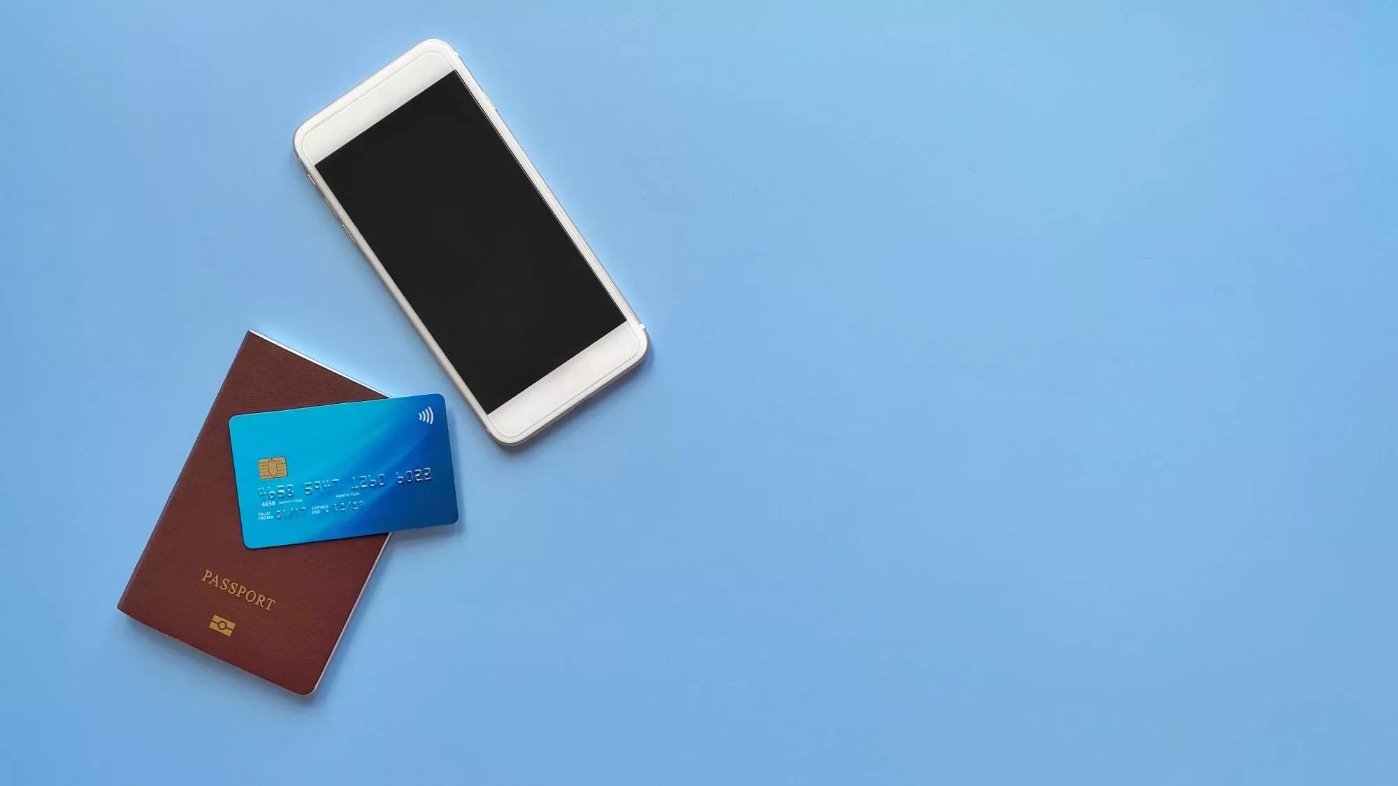 a smartphone, passport, and credit card that will incur an ISA fee against a blue background