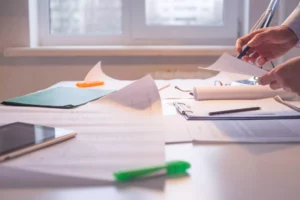 paperwork on a desk and a person reviewing merchant services for their company