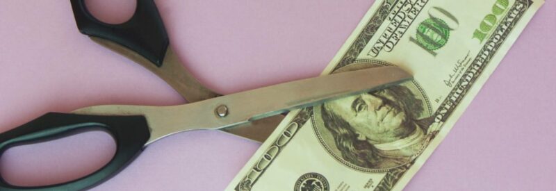 scissors cutting one hundred dollar bill against purple background symbolizing a close stripe account