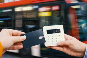 a mobile credit card reader with bus passing by in background symbolizing the clover go vs square debate