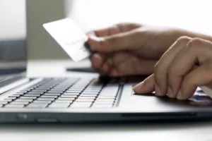 closeup of hands holding card and using laptop to search does afterpay build credit