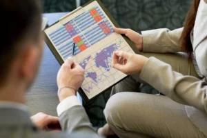 businessman and businesswoman looking at paperwork with global chart to identify their international service charge