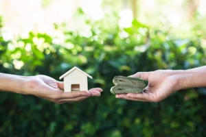 One hand holding cash to give to another hand holding a small house to show a collateral exchange necessary for microloans