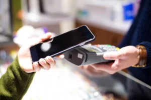 hand holding a terminal out to a customer who is holding their phone to pay after the business owner decided between square or stripe