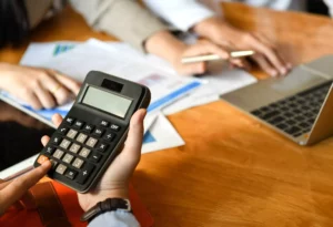 a business using a laptop and calculator to figure out stripe pricing