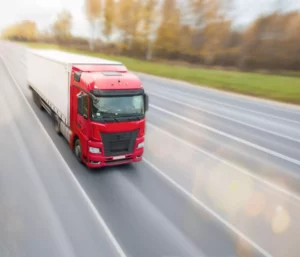 trucking business owner driving red and white truck down the highway 