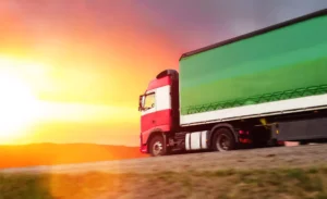 red and green truck looking at a sunset in the horizon owned by someone writing a trucking business plan