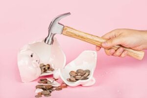piggie bank smashed with a hammer against pink background is what it feels like when you're charged the visa international service assessment
