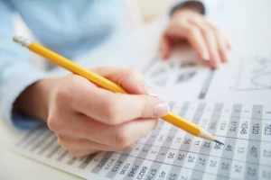 An accountant looking at their accounts receivable documents with a pencil 