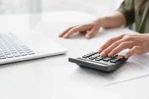 female processing an ach payment using a calculator and laptop