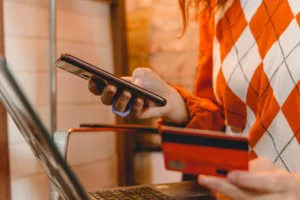 A person checking their phone for a refund policy to chargeback a purchase while holding credit card