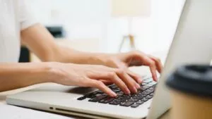 a person at their desk typing on a laptop to create an invoice