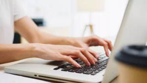 a person at their desk typing on a laptop to create an invoice