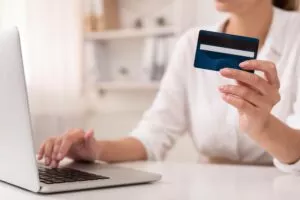 a woman putting in her cvv while using her laptop and holding her credit card