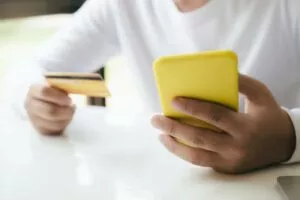 man holding phone and card setting up his Facebook Pay account online