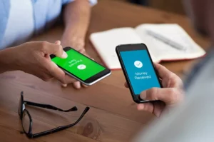 two people who found out how does facebook pay work, holding their phones to send money digitally at a desk. 