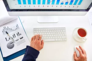 a person on their computer looking up how to increase sales with a cup of tea and a chart of sales