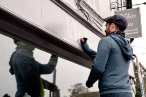 Man writing his business name on his shop after learning how to name a business 