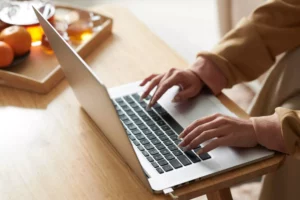 a woman at a table typing on her laptop how to set up facebook pay.