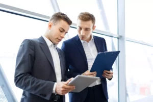 two business men looking at sales increase for the month on their clipboard