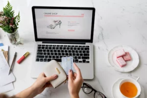 a woman at her desk in front of a laptop that shows buying from a sezzle merchant while she holds her wallet and credit card 