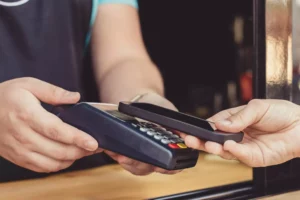 a customer using sezzle payments in store on a terminal by holding a phone to a terminal that a worker holds