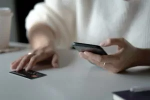 a person holding their phone and a credit card while storing credit card info