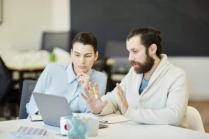 brand managers sitting in front of a laptop at an office discussing story branding for their company