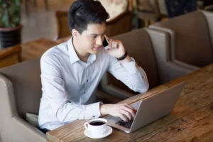 a business owner taking a telephone order at a restaurant while typing into virtual terminal on laptop