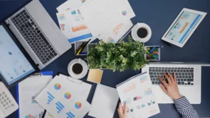 an accountant looking up what is a cpa with their laptop on a desk full of accounting documents 