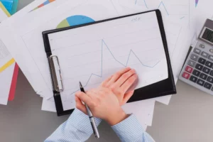 an accountant making a graph on a clipboard with a calculator after looking up what is a cpa license