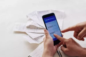 with receipts in the background, two people look at mobile banking app on smartphone and ask what is an eCheck 