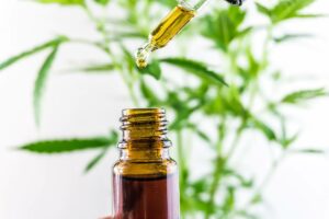 someone using eyedropper tool to put cbd oil in a bottle to show the difference from kratom