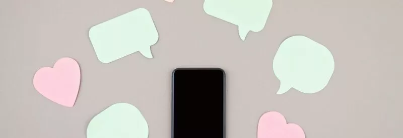 a phone on a gray background that shows social media marketing tools such as the like and comment symbol