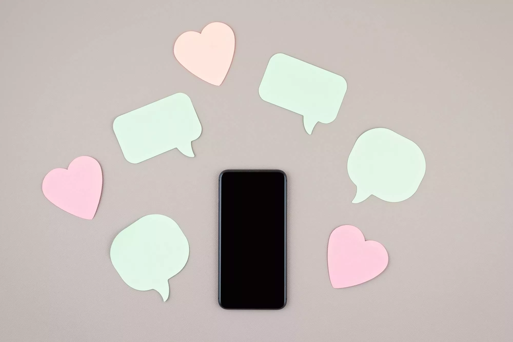 a phone on a gray background that shows social media marketing tools such as the like and comment symbol